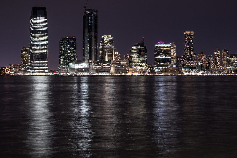 High-rise buildings glittering at night by a river